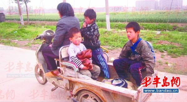 2011年底一名孩子在三輪車上趕作業(yè)。一年半過去了，這樣的場景仍隨處可見。